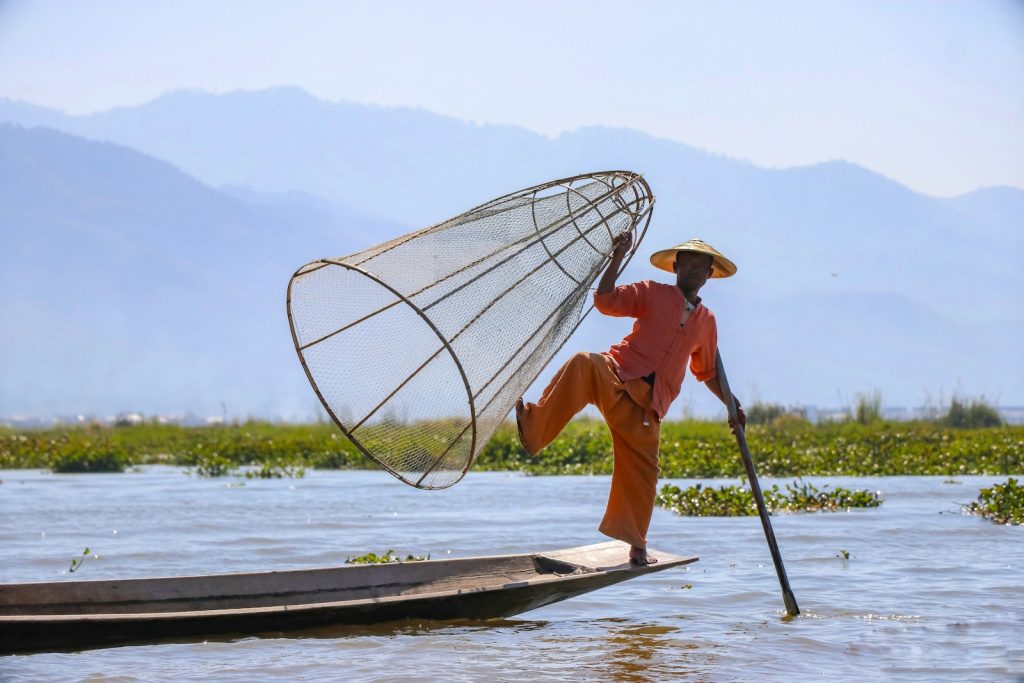 Photo by James Zhao woman in orange shirt and brown hat standing on white boat on sea during daytime