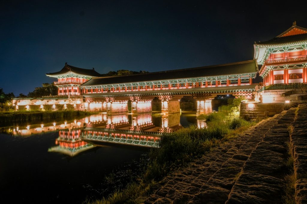 Photo by insung yoon a building lit up at night next to a body of water