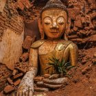a buddha statue sitting in the middle of a pile of rubble