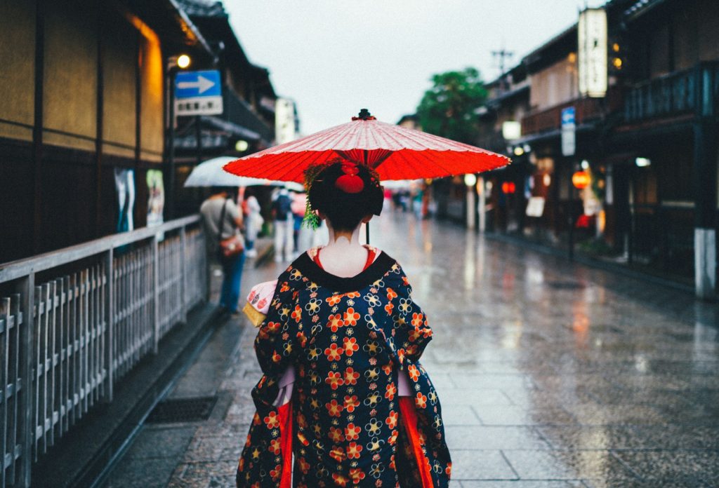 Photo by Tianshu Liu woman holding oil umbrella near on buildings