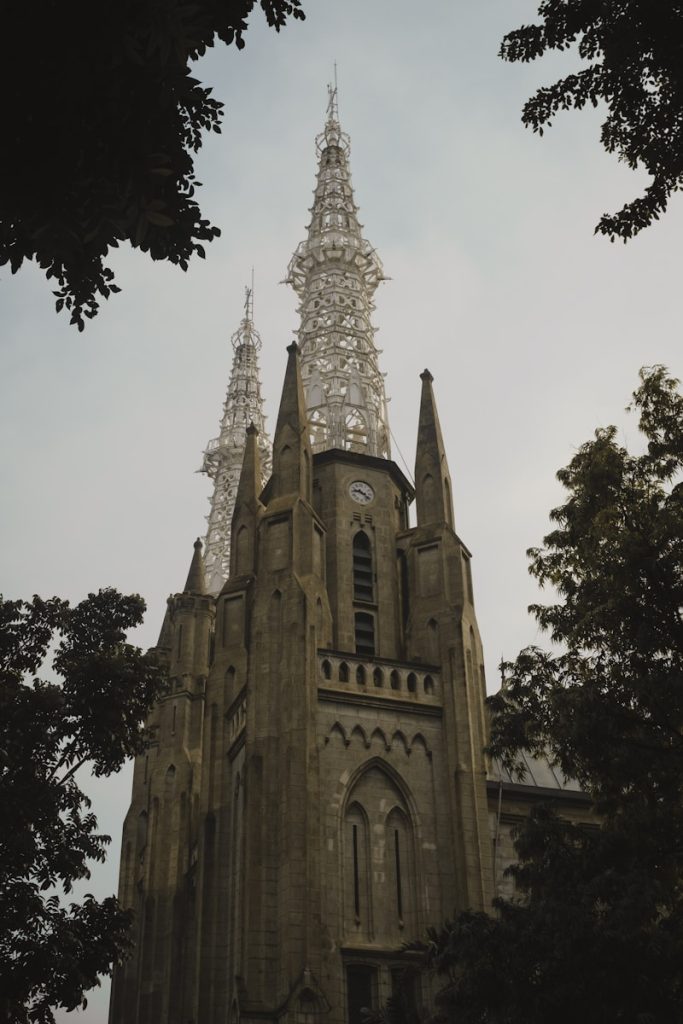 Photo by teguh pratama a very tall building with a clock on it's side