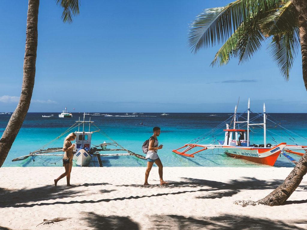 Photo by RJ Baculo woman in pink bikini walking on beach during daytime