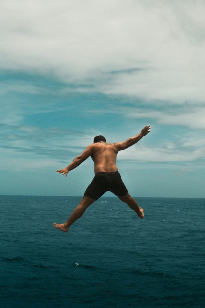 Photo by Mounish Raja A man jumping into the air over the ocean