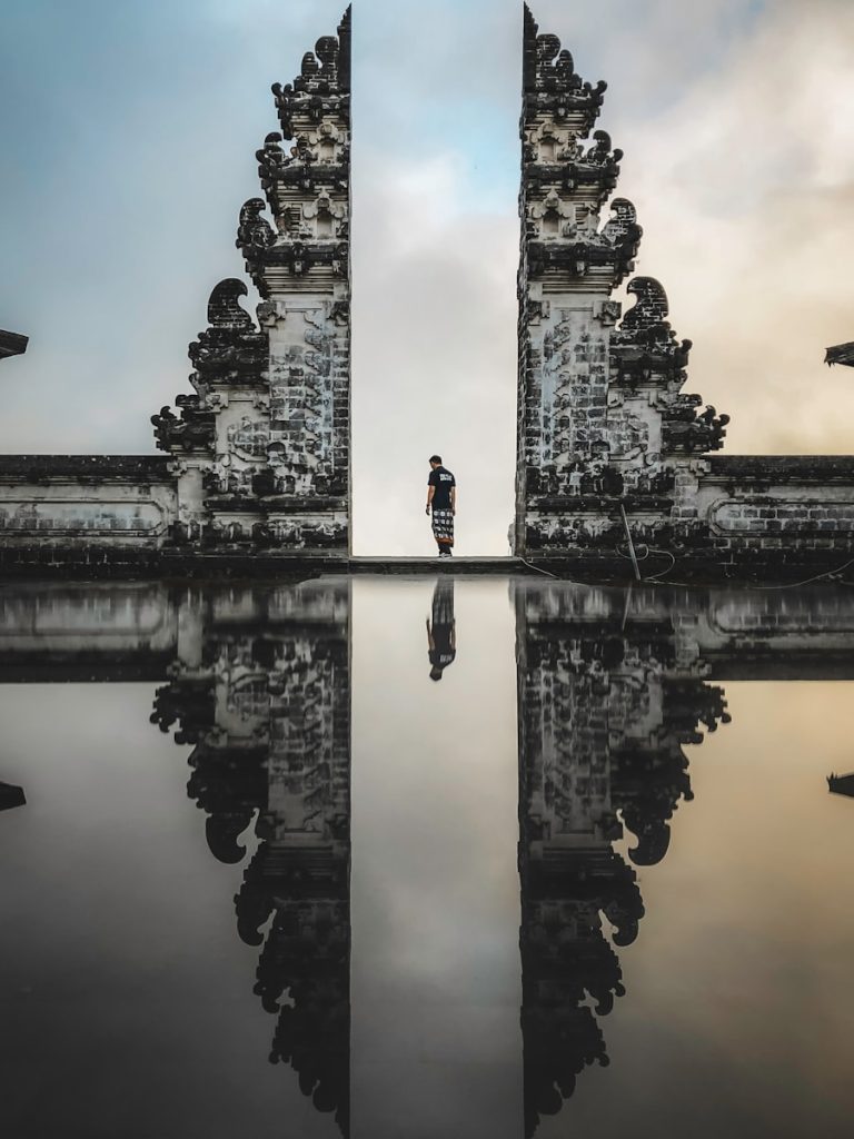 Photo by Road Trip with Raj man standing between ruins in reflective photography