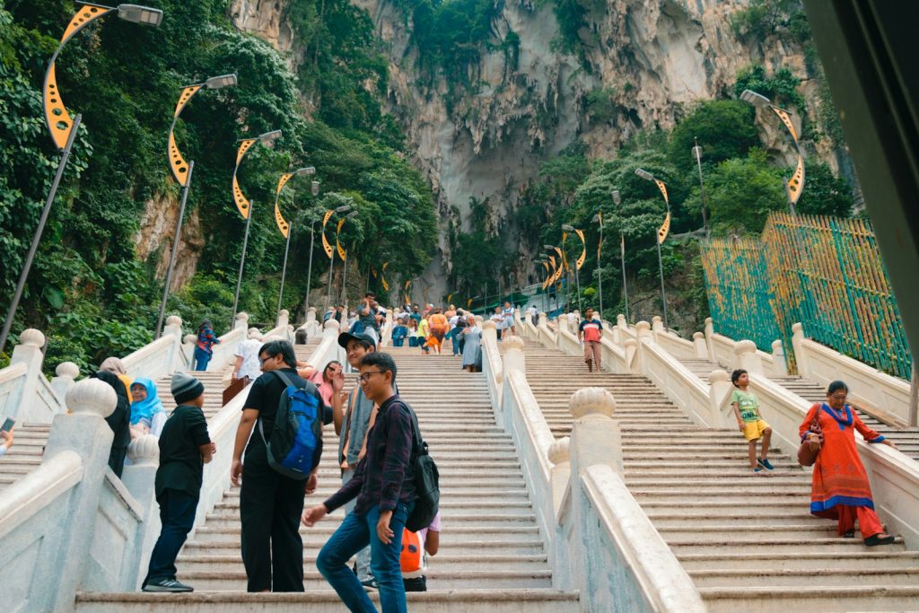 Photo by Job Savelsberg a group of people walking up stairs with Batu Caves in the background