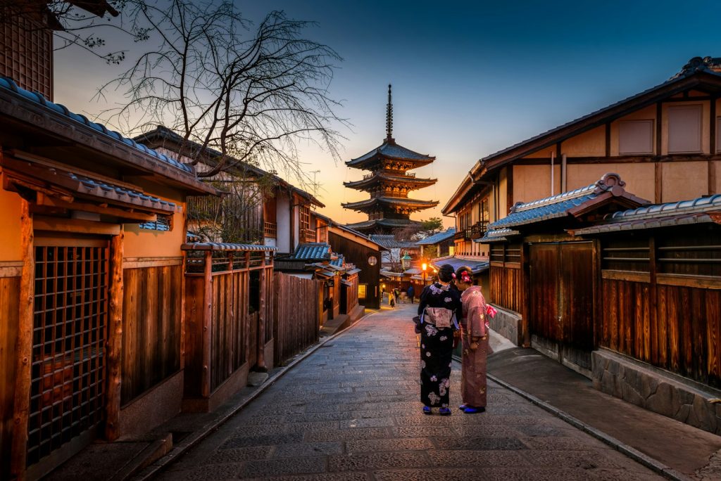 Photo by Sorasak two women in purple and pink kimono standing on street
