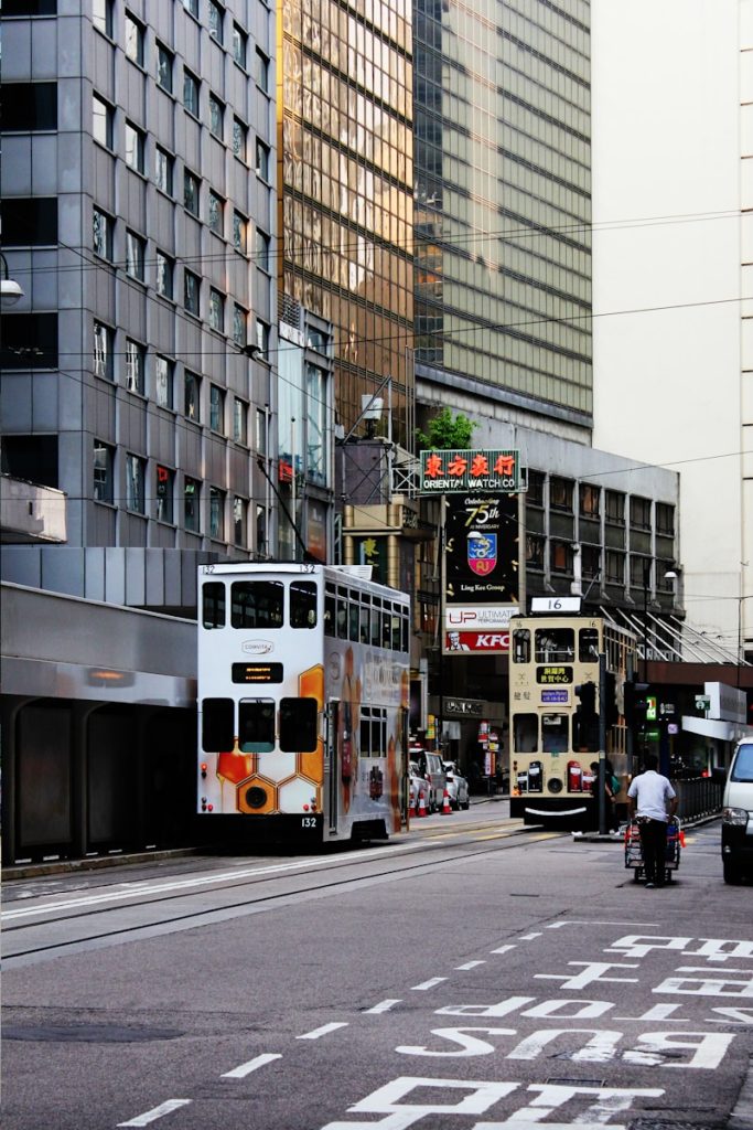 Photo by Ka Ho Ng a double decker bus driving down a street next to tall buildings